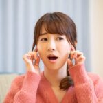 顎関節を指で押さえながら口を開ける女性
