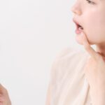 銀歯が気になって鏡で奥歯を見ている女性