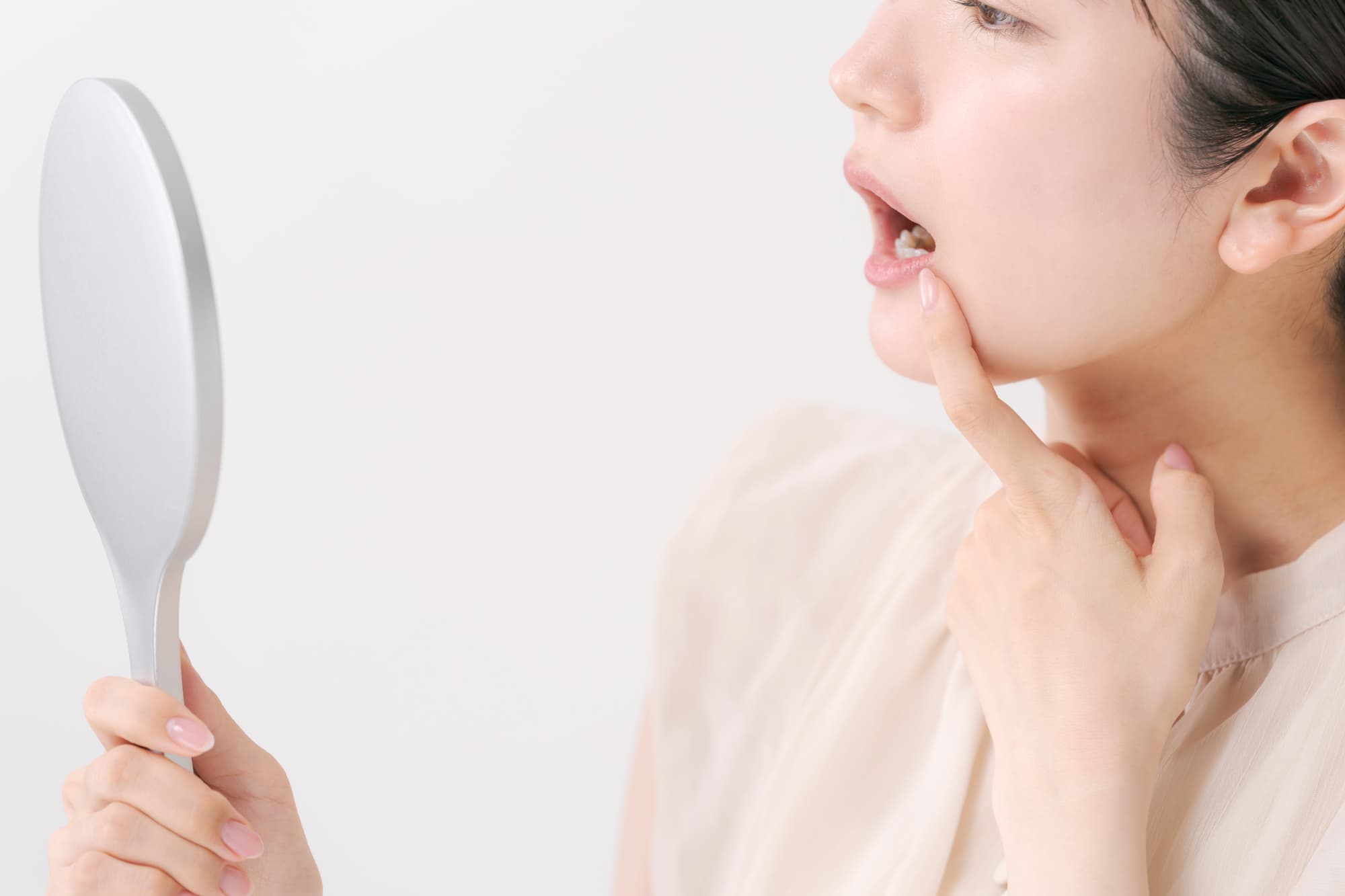 銀歯が気になって鏡で奥歯を見ている女性